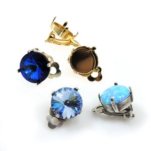 May include: Four earring settings with different colored stones. Two settings are gold with a blue and a clear stone. Two settings are silver with a blue and an opal stone.