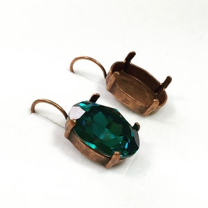 May include: A pair of copper earring settings with a deep green oval-shaped gemstone. The settings are designed to hold a large stone.