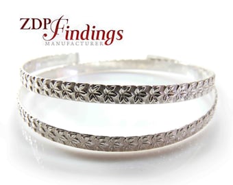 May include: Two silver bracelets with a floral design. The bracelets are stacked on top of each other.