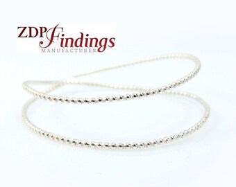 May include: A silver beaded bangle bracelet with a double-wrap design. The bracelet is made of small, round beads that are evenly spaced along the wire. The bracelet is simple and elegant, and it would make a great gift for any occasion.