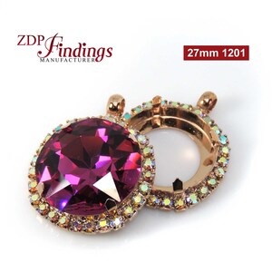 Puede incluir: Un colgante redondo de 27 mm con un acabado en oro rosa y un gran cristal facetado de color fucsia rodeado por un halo de cristales más pequeños e iridiscentes. El colgante está abierto en la parte posterior, lo que permite insertar una foto u otro adorno.