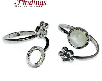 Könnte beinhalten: Zwei verstellbare Silberringe mit Blumenmotiven. Ein Ring hat einen runden weißen Stein mit einer silbernen Einfassung. Die Ringe befinden sich auf einem weißen Hintergrund.