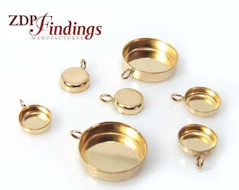 May include: Gold-colored jewelry findings in various sizes, including round bezels with loops for pendants or charms. The image shows several pieces with a shiny, metallic finish, perfect for crafting. The text "ZDP Findings Manufacturer" is visible.