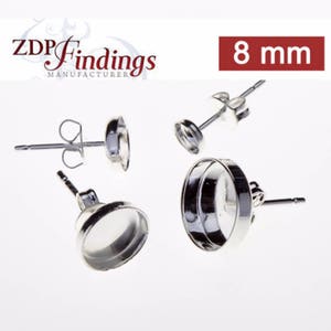 May include: Silver earring settings with 8 mm round bezels. The bezels are designed to hold a cabochon stone.