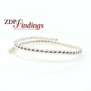 May include: A silver beaded bangle bracelet. The bracelet is made of small, round beads that are connected together to form a continuous loop. The bracelet is open ended and can be adjusted to fit different wrist sizes.