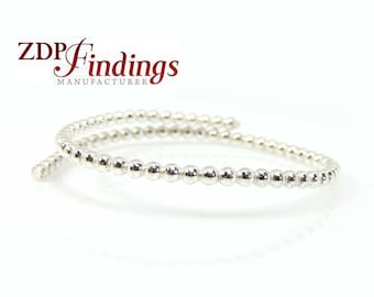 May include: A silver beaded bangle bracelet. The bracelet is made of small, round beads that are connected together to form a continuous loop. The bracelet is open ended and can be adjusted to fit different wrist sizes.