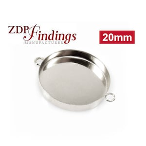 May include: Silver-toned round pendant tray with a 20 mm diameter. The tray has a smooth, shiny surface and two small loops on the side for attaching a chain or cord.
