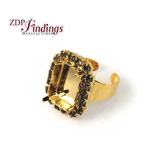 Könnte beinhalten: Goldener Ring-Fassung mit einer quadratischen Fassung und klaren Strasssteinen am Rand. Der Ring ist hinten offen und hat eine glatte, polierte Oberfläche.