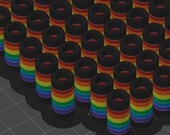 Puede incluir: Una matriz de carretes negros con bandas de colores del arcoíris. Los carretes están dispuestos en un patrón de cuadrícula, con los colores del arcoíris visibles en los lados. Los carretes están sobre una superficie gris oscuro.