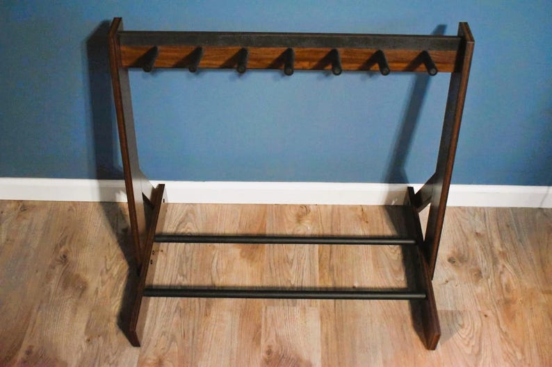 May include: A mid-century modern coat rack made of dark wood with six hooks. The rack has a rectangular frame with a horizontal bar at the bottom for storage. The design is minimalist and functional, suitable for entryways or bedrooms.