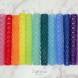 Puede incluir: Un conjunto de 15 velas de panal en varios colores, incluyendo blanco, rosa, lavanda, rojo, naranja, amarillo, verde, azul, morado y negro. Las velas est&aacute;n dispuestas en un patr&oacute;n de arco&iacute;ris.