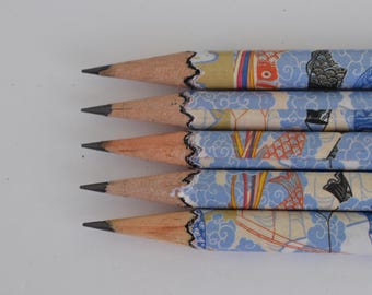 Könnte beinhalten: Nahaufnahme von fünf angespitzen Bleistiften mit hellblauen Mustern. Die Bleistifte haben einen Holzkörper und eine schwarze Graphitspitze. Das Muster zeigt Fische und andere japanisch inspirierte Motive.