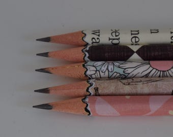 Könnte beinhalten: Nahaufnahme von fünf Bleistiften mit dekorativen Mustern. Die Bleistifte haben einen hellbraunen Holzkörper mit einer schwarzen Graphitspitze. Die Muster umfassen Blumen-, Diamanten- und Textdesigns in verschiedenen Farben.