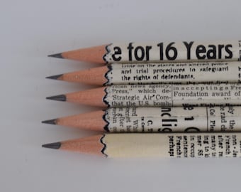 Könnte beinhalten: Sechs Bleistifte mit Zeitungspapier umwickelt. Die Stifte sind vertikal angeordnet, wobei der oberste Stift den Text "e for 16 Years" zeigt.