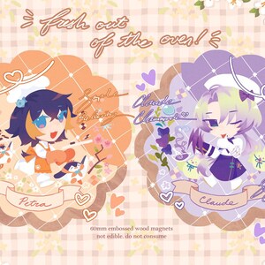 May include: Two 60mm embossed wood magnets with anime-style characters, Petra and Claude, set against floral and heart backgrounds. The magnets feature the text "fresh out of the oven!" and "not edible. do not consume."