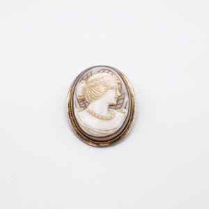 Könnte beinhalten: Eine weiße Keramik-Tasse mit schwarzem Henkel und dem Text "But First, Coffee" in schwarzer, handschriftlicher Schrift. Die Tasse steht auf einer weißen Oberfläche.