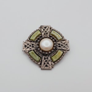 May include: A silver Celtic cross brooch with a faux pearl center and green stone accents.