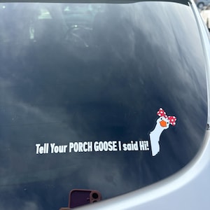 May include: A white vinyl decal on a car window featuring a goose head wearing a red and white polka dot bow, accompanied by the white text that reads: Tell Your PORCH GOOSE I said Hi!