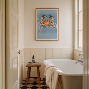 May include: A white bathtub with a white towel on the side, a small wooden stool with a bottle of soap and a tray on top, and a framed print of a blue crab on the wall above the bathtub.