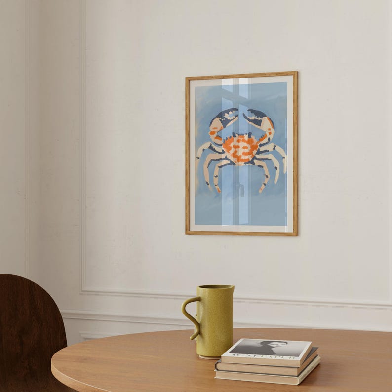May include: A framed print of a colorful crab on a light blue background. The crab is painted in shades of orange, blue, and white.