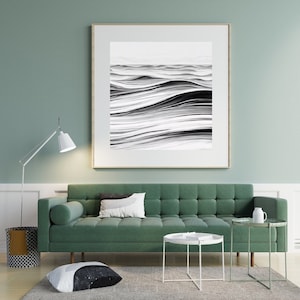 Könnte beinhalten: Ein grünes Sofa mit einem weiß-schwarzen Kissen, einem weißen Couchtisch und einem schwarz-weißen Bodenkissen vor einem gerahmten schwarz-weißen abstrakten Kunstdruck an einer grünen Wand.