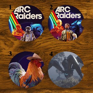 May include: Four round car coasters with different designs. Two coasters feature the text "ARC Raiders" with colorful graphics and characters. The other two coasters have a rooster wearing a cowboy hat and a robotic spider.