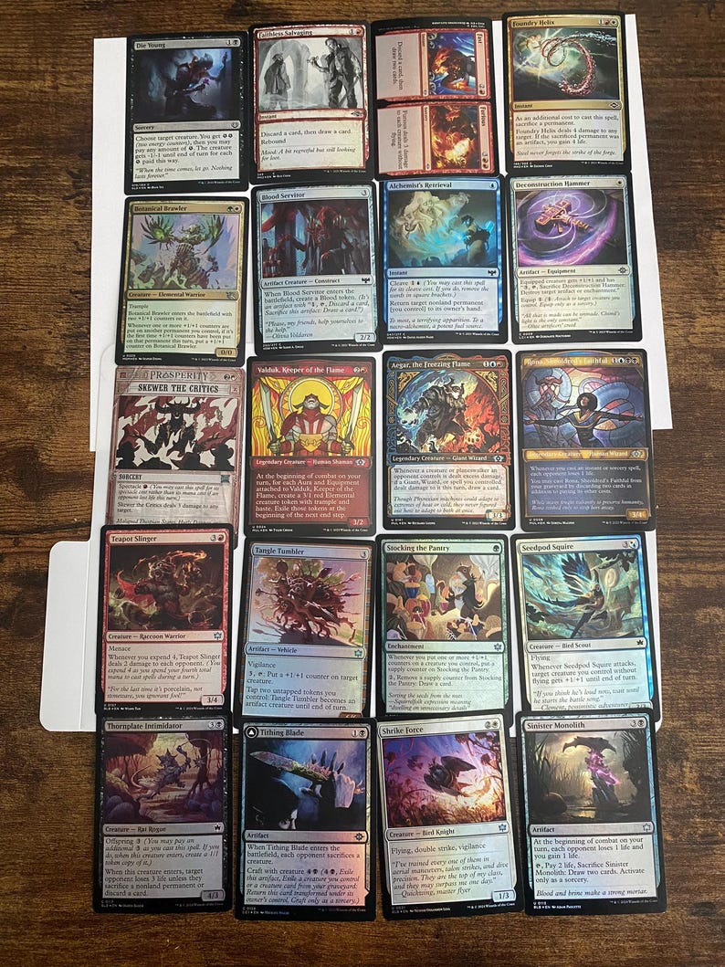 May include: A collection of Magic: The Gathering trading cards, featuring various card designs with fantasy art and text. The cards are arranged on a white surface, showcasing a variety of colors and illustrations.