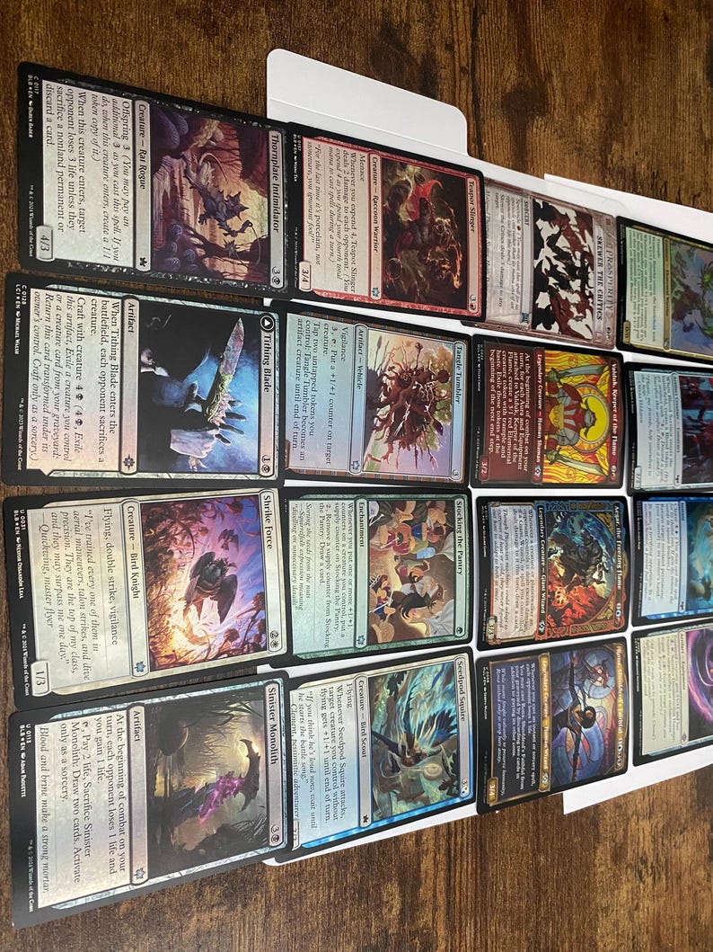 May include: A collection of Magic: The Gathering trading cards, featuring various creature and artifact cards. The cards display colorful illustrations and text, with card names like "Offspring", "Tithing Blade", and "Sinister Monolith".
