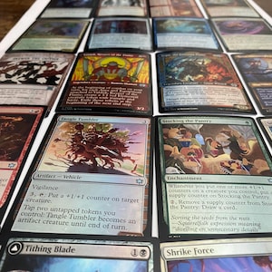 May include: A collection of Magic: The Gathering trading cards, featuring various card designs and artwork. The cards are arranged on a white surface, showcasing a variety of colors and illustrations. Some cards have text descriptions.