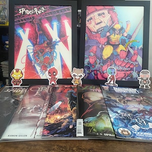 May include: A collection of comic books featuring characters like Spider-Punk, Wolverine, and the Inhumans. The comic books are displayed on a wooden surface with small figurines of Iron Man, Deadpool, Rocket Raccoon, Gamora, and War Machine.
