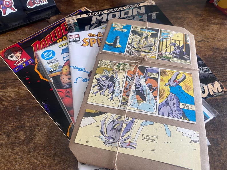 Pu&ograve; includere: Una pila di fumetti tra cui Moon Knight, Daredevil e The Amazing Spider-Man, con sopra un pacchetto avvolto in carta marrone e legato con dello spago. Il pacchetto presenta vignette a colori raffiguranti creature simili a gargoyle.