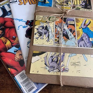 Pu&ograve; includere: Una pila di fumetti tra cui The Amazing Spider-Man numero 52, accanto a un pacchetto rettangolare avvolto in carta marrone. Il pacchetto &egrave; legato con uno spago sottile e decorato con vignette di fumetti raffiguranti una creatura viola.
