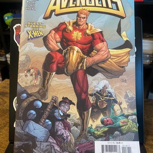 May include: Comic book cover featuring The Avengers with a guest appearance by the X-Men. The cover features a red and gold superhero with a cape, a group of superheroes in the background, and the text "The Avengers" in large, bold letters.