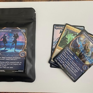 May include: A black pouch with a Magic: The Gathering card featuring two figures and the text "Unauthorized Exit." Three other cards are visible, including "Quicksilver," "Feast of the Victor," and "Dramatic Accusation."