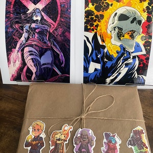 Pu&ograve; includere: Due stampe artistiche di fumetti con Psylocke e Ghost Rider, posizionate dietro un pacchetto avvolto in carta marrone e legato con spago. Il pacchetto &egrave; decorato con cinque piccoli adesivi di personaggi Marvel tra cui Captain Marvel.