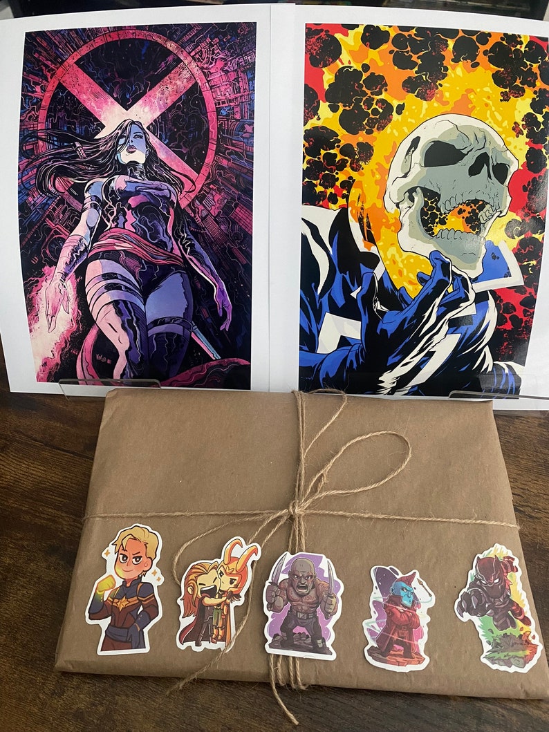 Pu&ograve; includere: Due stampe artistiche di fumetti con Psylocke e Ghost Rider, posizionate dietro un pacchetto avvolto in carta marrone e legato con spago. Il pacchetto &egrave; decorato con cinque piccoli adesivi di personaggi Marvel tra cui Captain Marvel.