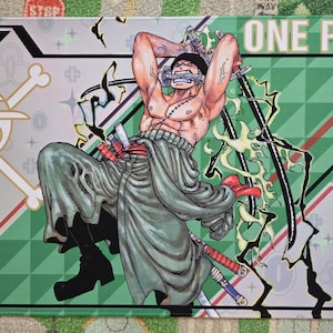 May include: A One Piece playmat featuring a muscular character with swords, wearing a head covering and draped in a green garment. The background has a green and white geometric design with the text "ONE PIECE" and the number "0414/1000".