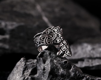 May include: A silver ring featuring a Celtic knot design. The ring is displayed against a dark grey background.