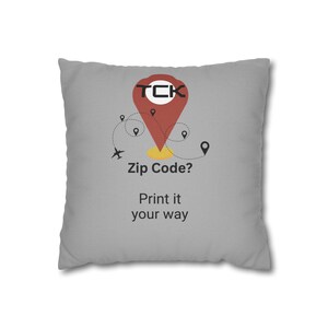 May include: Grey throw pillow with a red and yellow graphic of a location pin with the text "TCK Zip Code? Print it your way".