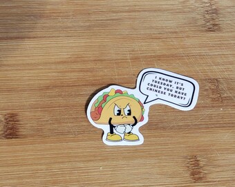 May include: A sticker featuring an anthropomorphic taco with an angry expression. The taco has a yellow shell, green lettuce, red tomatoes, and a speech bubble that reads, "I know it's Tuesday, but could you have Chinese today?"