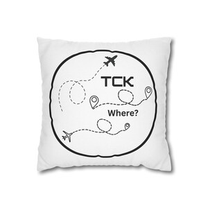 Puede incluir: Almohada blanca con un diseño circular negro. El círculo presenta un avión, una línea punteada y el texto "TCK Where?"