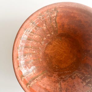 Pu&ograve; includere: Primo piano di una ciotola color terracotta con un design ampio e poco profondo. L'interno della ciotola presenta una superficie strutturata con striature di marrone chiaro e bianco, creando un aspetto rustico. La ciotola &egrave; probabilmente fatta a mano.
