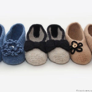 May include: Three pairs of crocheted slippers with different embellishments. The first pair is blue with a flower design, the second pair is beige with a black bow, and the third pair is brown with a flower design.