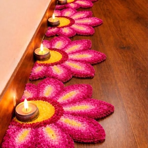 May include: Four flower-shaped floor mats arranged in a row, each featuring a bright yellow center surrounded by layered pink and magenta petals. A small, lit tea light candle in a metallic holder sits in the center of each mat.