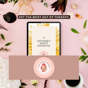 May include: A pink and brown digital tablet with a sunflower graphic on the screen. The text on the screen reads "the MINDSET SHIFT JOURNAL". The tablet is on a pink surface with flowers and a white cup.
