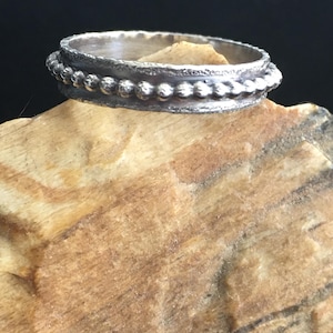 Pu&ograve; includere: Una tazza di ceramica bianca con manico nero e la scritta "But First, Coffee" in grassetto nero. La tazza &egrave; posta su uno sfondo neutro, evidenziando il suo design semplice.