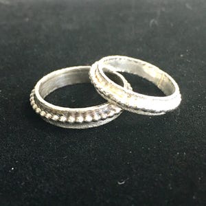 Pu&ograve; includere: Un set di tre tazze in ceramica con finitura opaca e macchiettata. Le tazze sono nei toni del crema, grigio chiaro e grigio scuro. Ogni tazza ha un design semplice e minimalista e un manico arrotondato. Le tazze sono impilate.