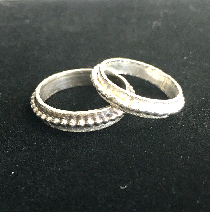 Pu&ograve; includere: Un set di tre tazze in ceramica con finitura opaca e macchiettata. Le tazze sono nei toni del crema, grigio chiaro e grigio scuro. Ogni tazza ha un design semplice e minimalista e un manico arrotondato. Le tazze sono impilate.