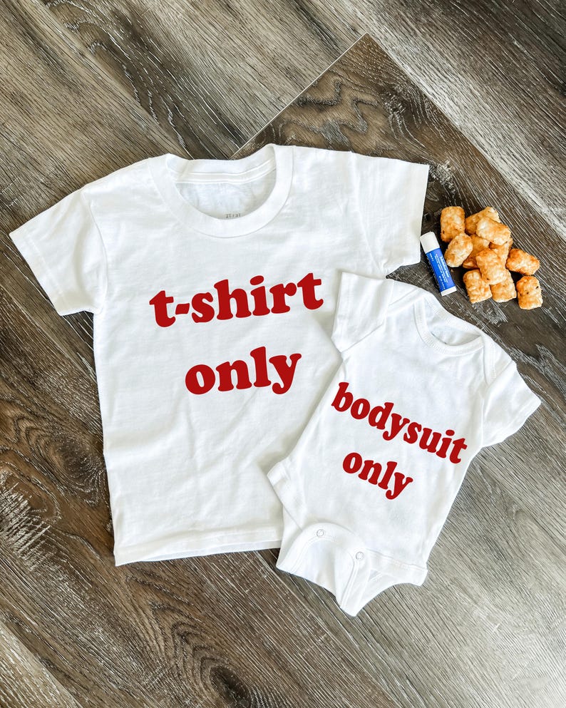 May include: Two white shirts with red text. The larger shirt says "t-shirt only" and the smaller shirt says "bodysuit only".