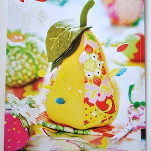 May include: A set of five colorful pincushions shaped like a pear, apple, tomato, and two strawberries. The pincushions are made of fabric and have a patchwork design. The image includes the text "fresh picked Pincushions a pear, an apple, a tomato & two strawberries".